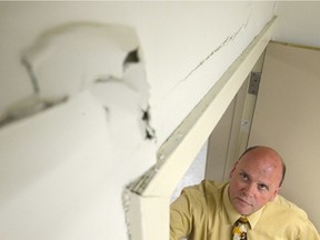 Shawn Pearce, principal of École St. Pius X, looks up at cracks that have formed in the walls of a classroom.