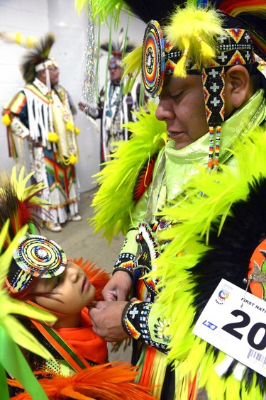 Amos Zazzie, right, adjusts his son's headdress before the grand entry at the First Nations University of Canada spring powwow at the Brandt Centre.