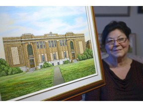 Professional artist Yvonne Kydd sits beside her original acrylic painting on canvas of Scott Collegiate at her home.