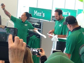 Saskatchewan Roughriders president-CEO Craig Reynolds cuts the ribbon at the grand opening of the team's new Mosaic Stadium stor on Saturday while flanked by players Chad Owens (taking picture) and Dan Clark.