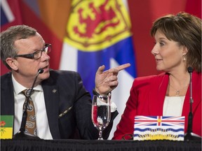 Premier Brad Wall gestures past B.C. Premier Christy Clark during the closing news conference at the First Ministers Meeting in Ottawa, Friday Dec. 9, 2016.