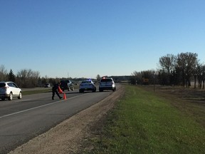 Regina police officers in the northbound lane of the Ring Road, north of the Wascana Parkway overpass on Wednesday morning. A man's body was found east of the roadway in a field.