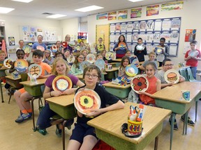 Students of Rachel Ling's grade five class hold up their plates at École St. Andrew School. The Food for Families fundraiser raises money by selling the plates on Ebay.