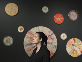 MacKenzie Art Gallery curator Michelle LaVallee sits in front of some Alex Janvier circle paintings.