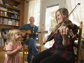 Musicians Tahnis Cunningham, right, and Ray Bell, centre, at their home while Nora Bell, left, claps along. The duo will play traditional Metis music at Tattoo Royale - Majesty in Motion May 23 and 24 at the Brandt Centre.