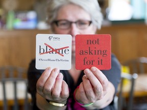 Cheryl Tovey, floor manager at Bushwakker Brewpub, sits at a table behind beer coasters. The coasters are part of the YWCA's 2017 Sexual Assault Prevention Campaign that works to end victim blaming and rape culture and adopt a consent culture.