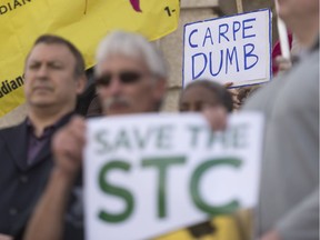 People hold signs at a rally against the STC closure at the Legislative Building.