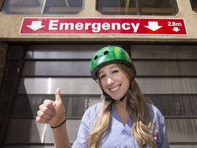 Dr. Emily Sullivan, a second-year medical student with the University of Saskatchewan's College of Medicine, poses with a bike helmet outside Royal University Hospital emergency Monday, May 12, 2014 while wearing a shirt that reads "Put me out of work, wear your bike helmet."