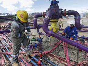 In this March 29, 2013 file photo, workers tend to a well head during a hydraulic fracturing operation outside Rifle, in western Colorado.