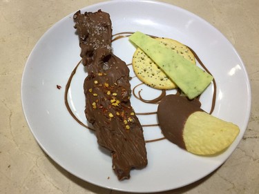 A charcuterie plate featuring a chocolate-dipped Pringle, sage cheddar cheese and milk chocolate-covered bacon.