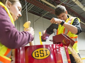 Mason Hodgson, right, uses a drill to power an auger grain while Abbigail Guse, right, helps during a demonstration by the Mobile Grain Demonstration and Training Unit. Aside from public education about grain safety, the Saskatchewan-made unit gives firefighters the skills they need to safely rescue someone trapped in grain.