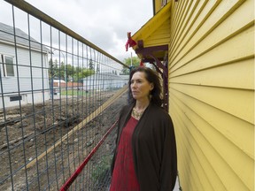 Angela Ell stands between her house at 2509 Atkinson St. and a security fence that stands around a recently demolished lot.