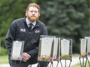 Chris Harris, amateur historian and photojournalist, kneels among his exhibit on the lawn near the Legislative Building. His photos commemorate the 47 Saskatchewan born soldiers who died on D-Day.