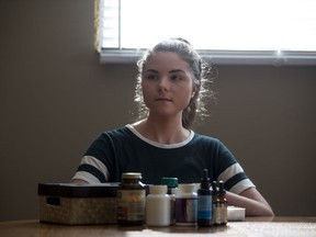 Anika Kosteniuk, who is 19 and has had chronic Lyme disease since she was 13, sits with some of the medication she takes on a daily basis.
