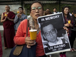 An exile Tibetan carries a portrait of late Nobel Peace Prize laureate Xiaobo Liu, China's most famous political prisoner, as she joins others during a candlelit vigil to mourn Liu's death, in Dharmsala, India, Friday, July 14, 2017. Liu died Thursday of liver cancer at 61.