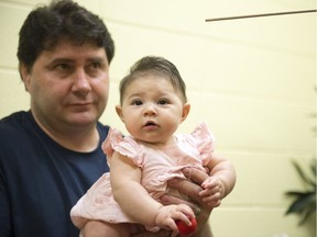 Tiana Sawa grabs a colourful ball while held by her father Grant at the Early Cognitive Development Lab at the University of Regina.