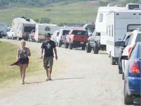 People walk while vehicles line-up to leave the Country Thunder festival campgrounds.