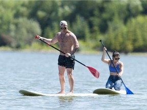Isaiah Dobni and Nicholette Thera paddle board on Wascana Lake during a sunny afternoon.