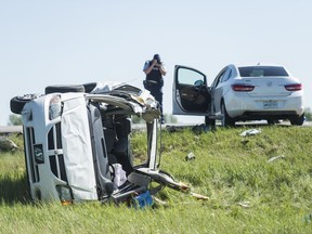 An RCMP member photographs the wreckage of a collision between a car and a minivan north of Regina on Highway 11.