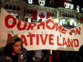 People hold up a sign during a demonstration on Parliament Hill, as a crowd gathered to erect a teepee as part of a four-day Canada Day protest, in Ottawa on Thursday, June 29, 2017.