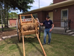 JULY 1, 2017 -- Clifton Abrahamson, past president of the Museum shows off the Museum's Red River Cart.  The new museum is in the background. PHOTO PROVIDED BY ALLAN REINE