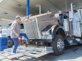 Joe Flege, a long-haul trucker from Winnipeg, closes the engine cover of his Kenworth at a Husky gas station.