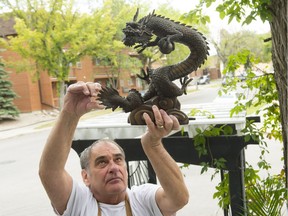 Rick Urbanski holds up a bronze dragon at the entrance to his business, Dragon's Nest B&B. An identically shaped but much larger version of the dragon was stolen from the entrance of the property.