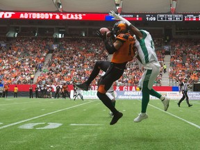 The B.C. Lions' Bryan Burnham, left, and the Saskatchewan Roughriders' Crezdon Butler battle for the football Saturday at BC Place.