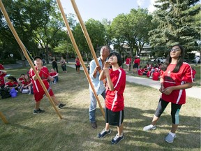 Leonard Daniels teaches Grade 8 students Fuka Kikuchi and Manha Ahmed during a teepee raising at Davin School on Thursday.