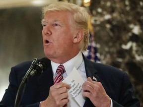 U.S. President Donald Trump reaches into his suit jacket Tuesday, Aug. 15, 2017 to read a quote he made on Saturday, Aug. 12, regarding the events in Charlottesville, Va., as he speaks to the media in the lobby of Trump Tower in New York.