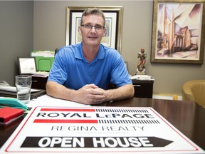 Mike Duggleby, a broker with Royal LePage Regina Realty, displays an open house sign on his desk in Regina.