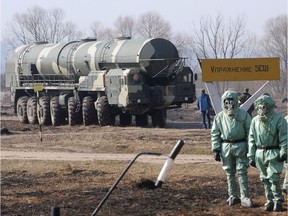 Russian soldiers wear chemical protection suits as they stand next to a military fueler on the base of a prime mover of a Russian Topol intercontinental ballistic missile during a training session at the Serpukhov's military missile forces research institute some 100km outside Moscow on April 6, 2010.