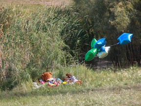 Stuffed animals and balloons sit at the edge of a retention pond near Ecole Dundonald in Saskatoon on Tuesday.