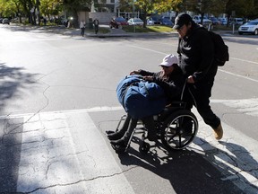 onathan McLeod pushes his mother Mary-Ann McLeod across the street with a duffle bag of their belongings piled on top of her after being evicted and spending the night sleeping outside in a park in Saskatoon on September 25, 2017.