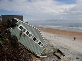 A house rests on the beach after collapsing off a cliff from Hurricane Irma in Vilano Beach, Fla., Friday, Sept. 15, 2017. Florida‚Äôs economy has long thrived on one major import: people. Irma raised concerns about just how sustainable the allure of Florida‚Äôs year-round warmth and lifestyle are. The wind, rain and flooding inflicted an estimated $50 billion in damage. (AP Photo/David Goldman)