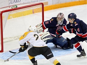 Connor Gutenberg, left, of the Brandon Wheat Kings flicks the puck past Regina Pats goaltender Tyler Brown during WHL pre-season action Friday at Westman Place.