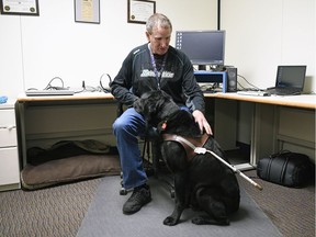 SaskTel employee Shan Noyes with his guide dog, Danson, in the office in Regina.