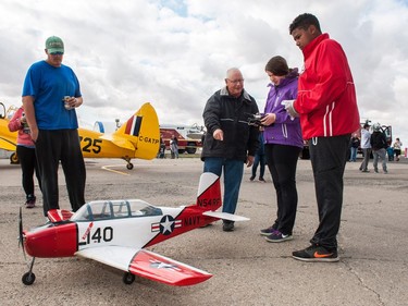 Doug Brownlee (center left) allows visitors a chance to operate his 1/5 scale T-34B Mentor remote controlled aircraft during the Regina Flying Club's open house event in Regina, Saskatchewan on September 17, 2017.