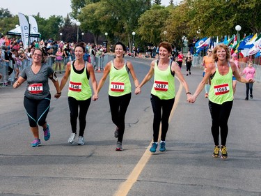 Participants cross the finish line together in front of the Conexus Arts Centre after completing a half marathon during the Queen City Marathon in Regina, Saskatchewan on September 10, 2017.