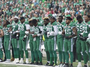 Saskatchewan Roughriders players link arms during the Canadian National Anthem during a CFL game held at Mosaic Stadium on September 24, 2017.