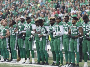 Saskatchewan Roughriders players link arms during the national anthem before Sunday's CFL game against the visiting Calgary Stampeders.