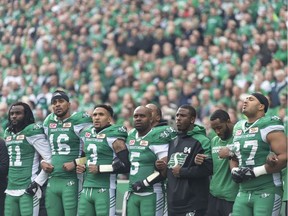 Saskatchewan Roughriders quarterback Kevin Glenn links arms with teammates during the Canadian National Anthem during a CFL game held at Mosaic Stadium on Sept. 24, 2017.