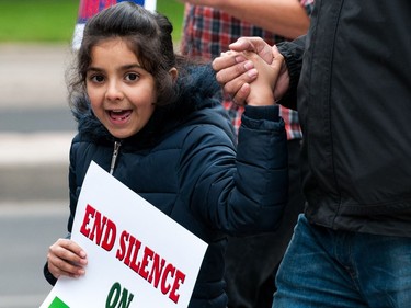 A child holds a sign while protestors march from city hall in Regina, Saskatchewan to rally against violence in western Myanmar. September 16, 2017.