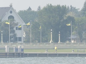 A man walks around Wascana Lake through air thick with forest fire smoke. The smoke is predicted to leave the city by Friday.