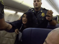 A screenshot of video showing a woman being removed from an airplane