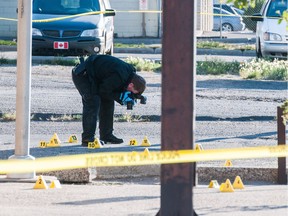 An investigator takes a photograph of a crime scene outside of a business on Victoria Avenue.