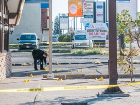 An investigator takes photographs of a crime scene outside of a business on Victoria Avenue.