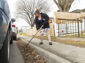 Chanelle Radons uses a stick to point out where water pools in front of her house on Toronto Street.