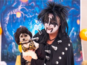 Tracey Isenor, dressed as Gene Simmons, holds her Papillon/Shitzu Mickey, dressed as a 'rocker chick,' during the Bark at the Moon dog Halloween costume contest Saturday, Oct. 28, 2017, in Regina.