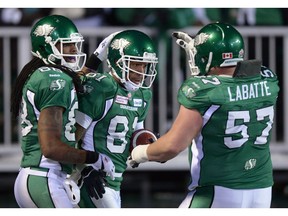 The Saskatchewan Roughriders' Brendon LaBatte, right, celebrates a touchdown by Geroy Simon, middle, during the 2013 Grey Cup game on Taylor Field. Taj Smith is on the left.